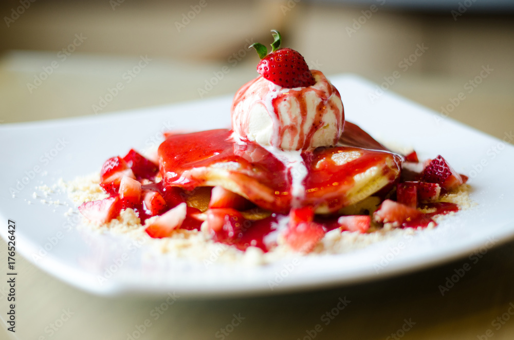 Pancakes with ice cream on top and then make up with strawberries on four white plates. Pancakes with ice cream on top and then make up with strawberries on four white plates.
