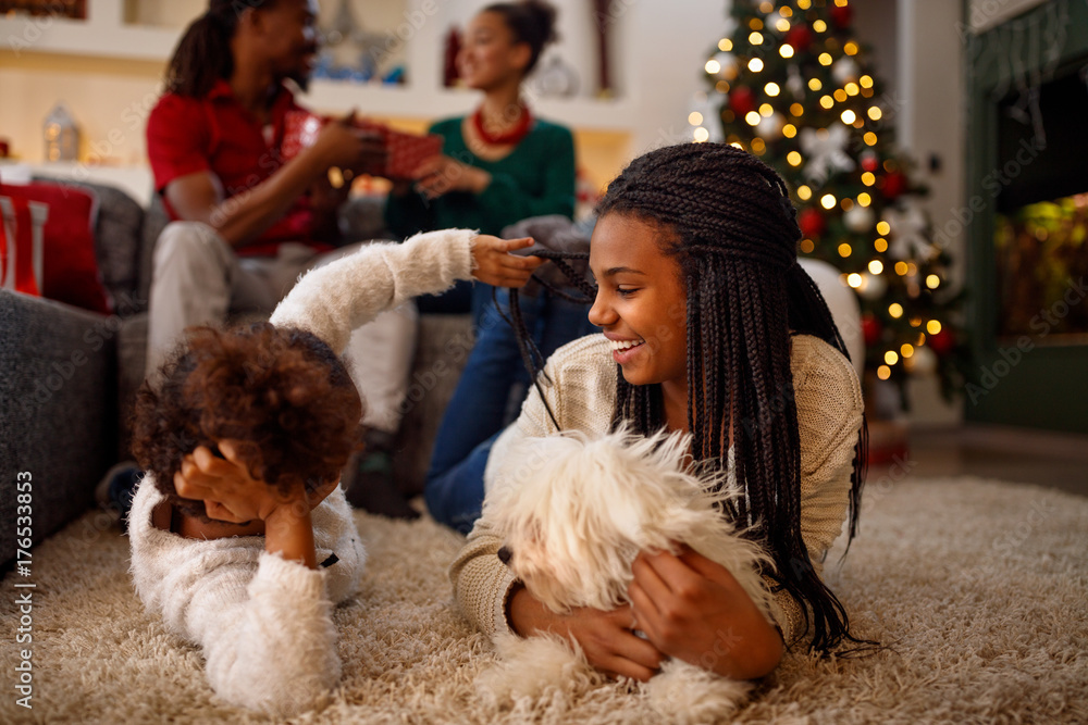 sisters are playing with dog and laughing. They are lying on floor near Christmas tree. sisters are playing with dog and laughing. They are lying on floor near Christmas tree.