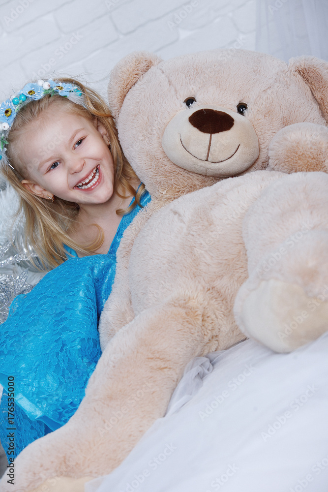 Fototapeta premium Cheerful blonde little girl lies on big soft toy bear