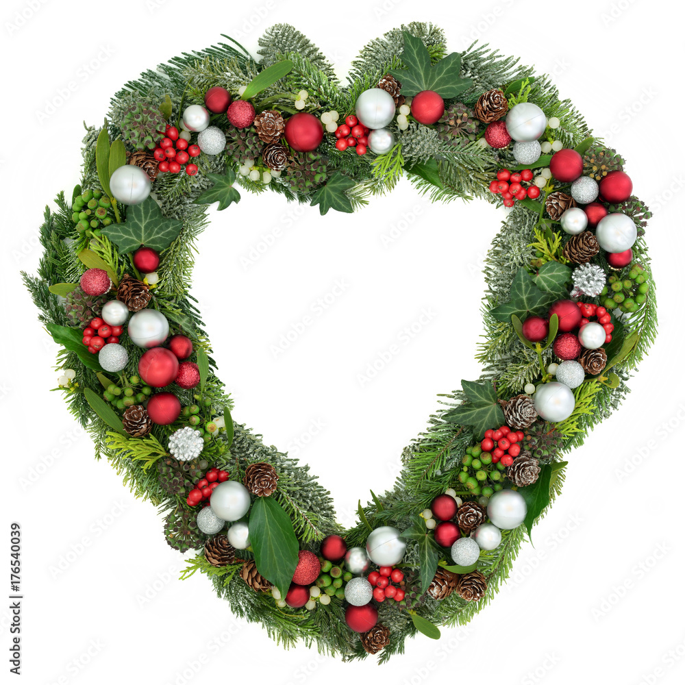 Christmas heart shaped wreath decoration with red and silver baubles, holly, mistletoe, juniper fir, blue spruce, cedar, pine cones and ivy on white background. Christmas heart shaped wreath decoration with red and silver baubles, holly, mistletoe, juniper fir, blue spruce, cedar, pine cones and ivy on white background.