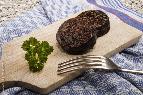 grilled irish black pudding made with oatmeal on a wooden board with knife