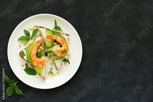 Sandwich with avocado, goat cheese, shrimp and arugula. View from above.