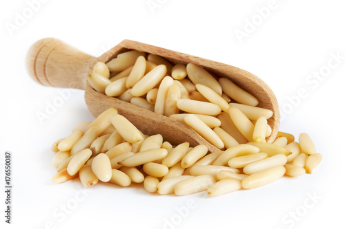 Raw pine nuts in wooden scoop isolated on white background