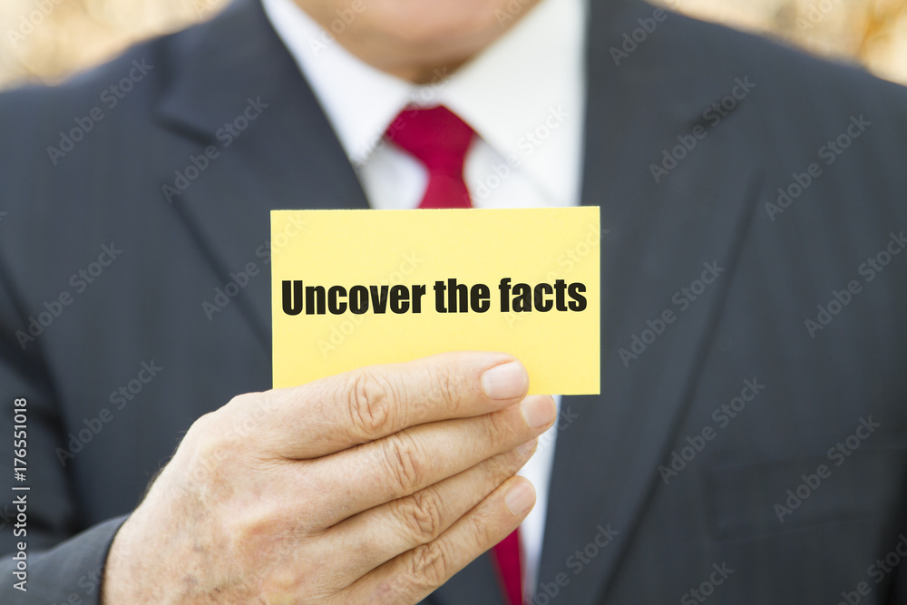 Businessman showing a card with text UNCOVER THE FACTS Businessman showing a card with text UNCOVER THE FACTS