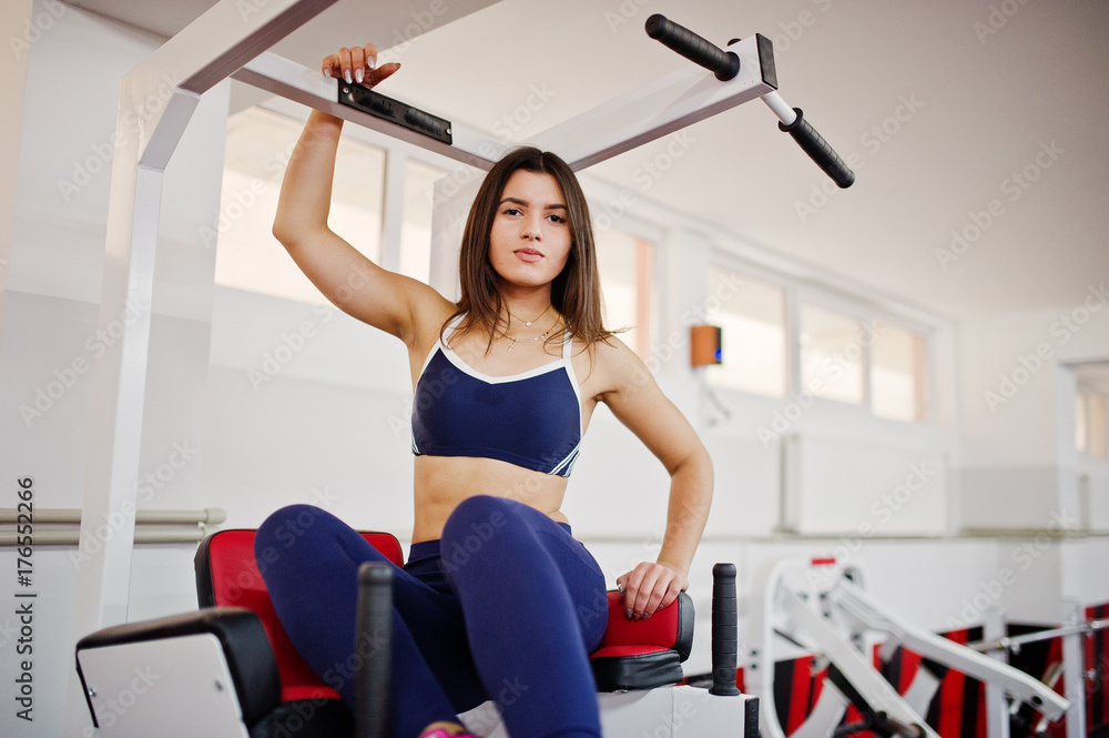 Fototapeta premium Young beautiful woman doing exercises and working hard in gym and enjoying her training process.