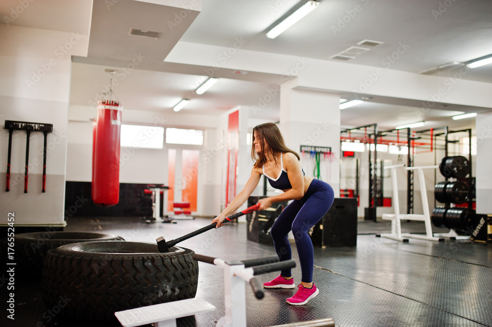 Fototapeta premium Young beautiful woman doing exercises and working hard in gym and enjoying her training process.