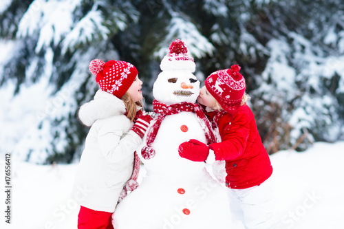 Kids building snowman. Children in snow. Winter fun. © famveldman