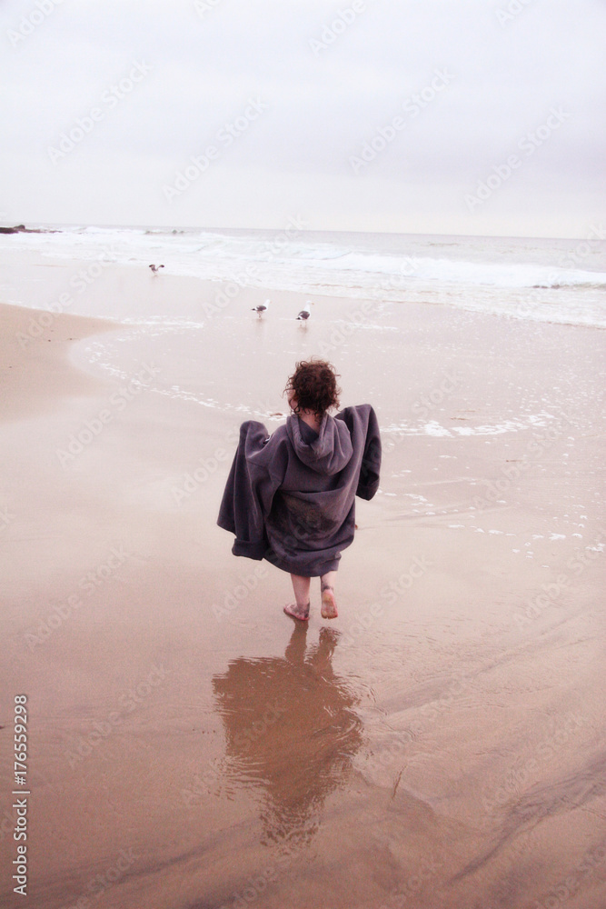 Little Girl In Oversized Sweatshirt Running On Beach Little Girl In Oversized Sweatshirt Running On Beach