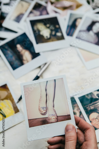 Hand holding a  photo of womens feet wearing high heeled shoes