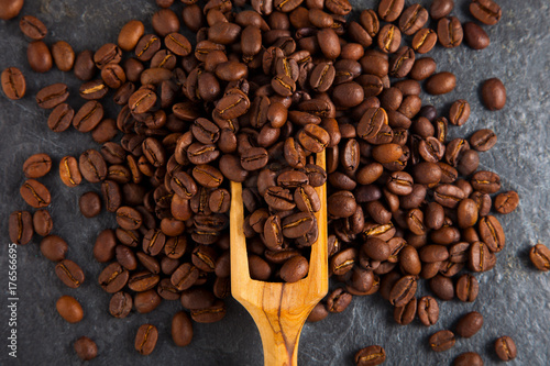 Coffee beans in a wooden scoop on slate plate background