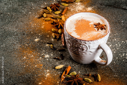 Traditional indian masala chai tea with spices - cinnamon, cardamom, anise, dark stone background. Copy space