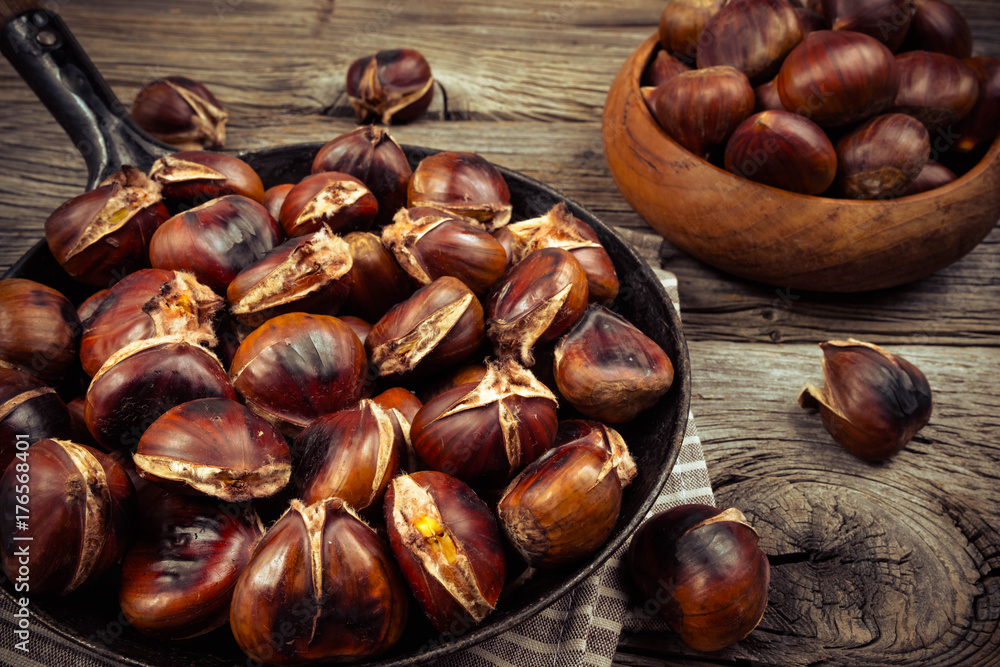 Obraz premium chestnuts in a pan on a wooden background