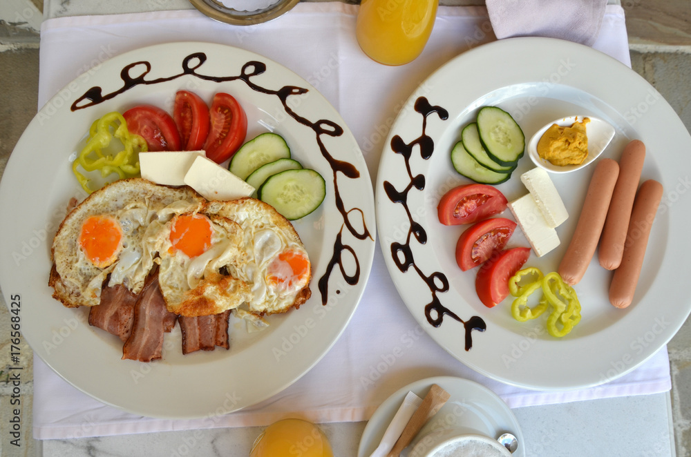 Plates with served breakfast - fried eggs, bacon, hot  eggs and fresh vegetables