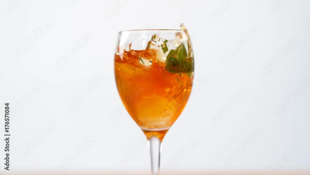 Ice cubes & fruit dropped into a glass of colorful summer cocktail Slowmo Ice cubes & fruit dropped into a glass of colorful summer cocktail Slowmo