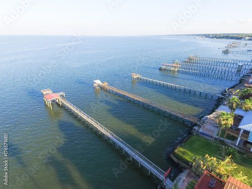 Aerial view three-story waterfront vacation home with fishing piers stretching out over the Galveston Bay in Kemah city, Texas, USA. Bird eye view of Kemah Lighthouse District at sunset. photo