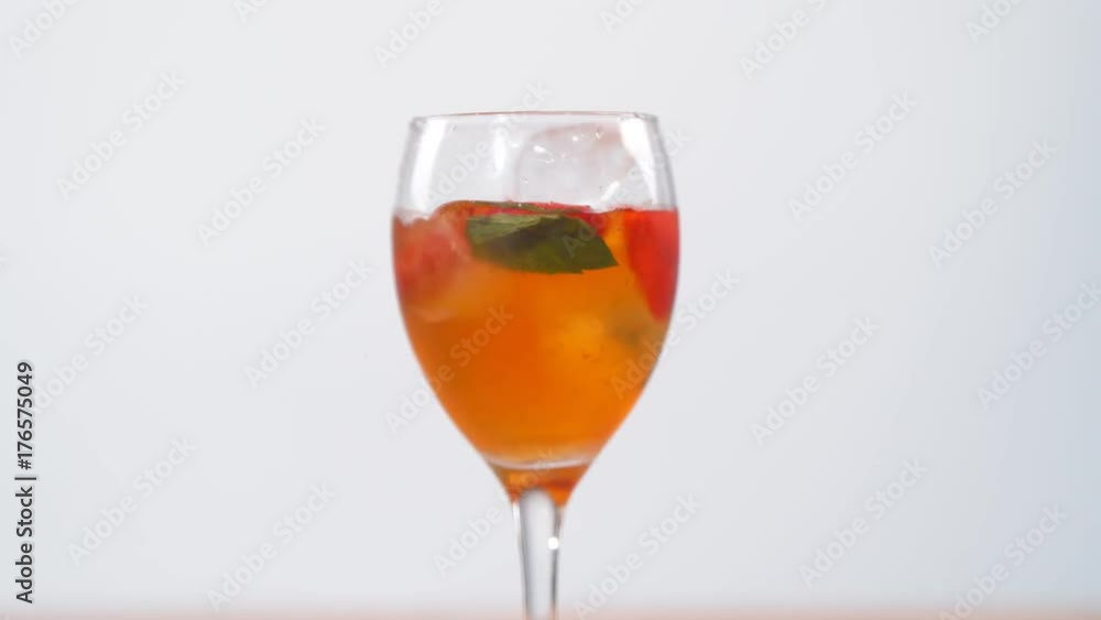 Ice cubes & fruit dropped into a glass of colorful summer cocktail Slowmo Ice cubes & fruit dropped into a glass of colorful summer cocktail Slowmo