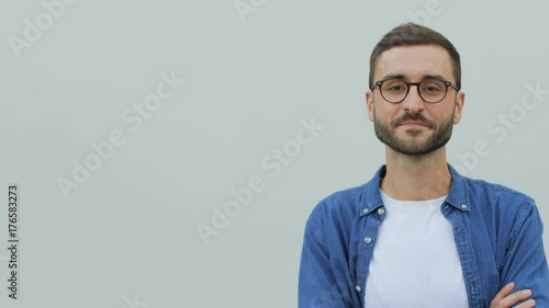 Portrait of a confident young man smiling and crossing his arms in the white background. Wearing a blue shirt