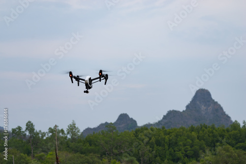 DJI Inspire, a standard quad-copter flying into Langkawi Rainforest National Park. Low angle view.
