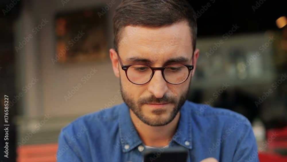 Closeup portrait of a handsome young man looking into his mobile phone in the cafe. Blurred background Closeup portrait of a handsome young man looking into his mobile phone in the cafe. Blurred background
