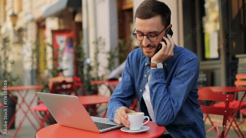 A portrait of an attractive and happy young man drinking coffee and talking on the phone. Blurred background A portrait of an attractive and happy young man drinking coffee and talking on the phone. Blurred background