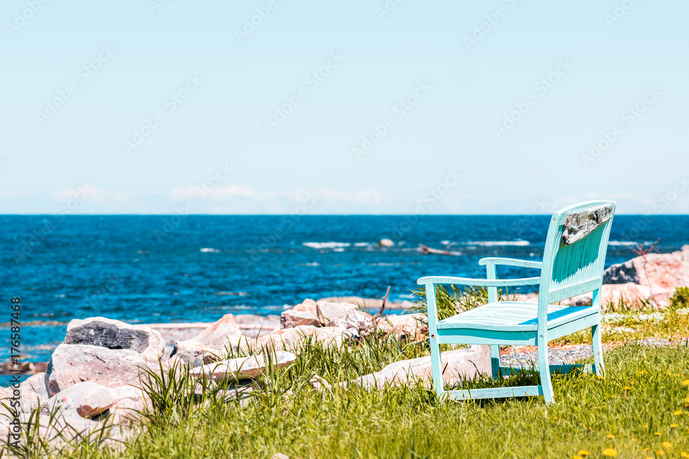 One peaceful blue aquamarine turquoise green beach chair empty bench in front of ocean
