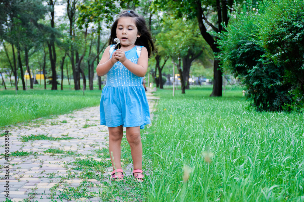 Little latin girl blowing dandelion in the summer park Little latin girl blowing dandelion in the summer park