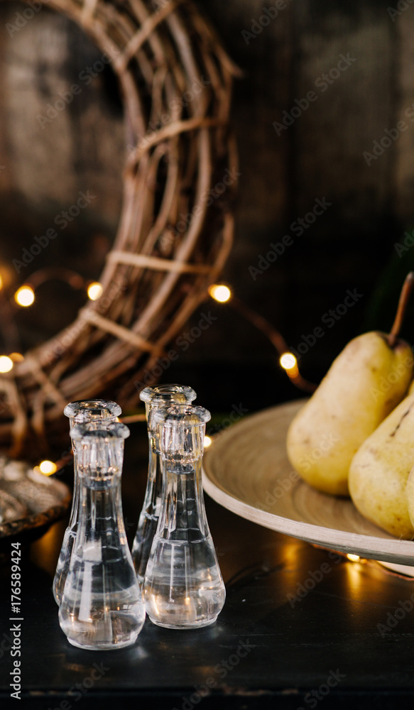 Beautiful decorated table with delicious organic pears and glasses,luminous lamps in the background