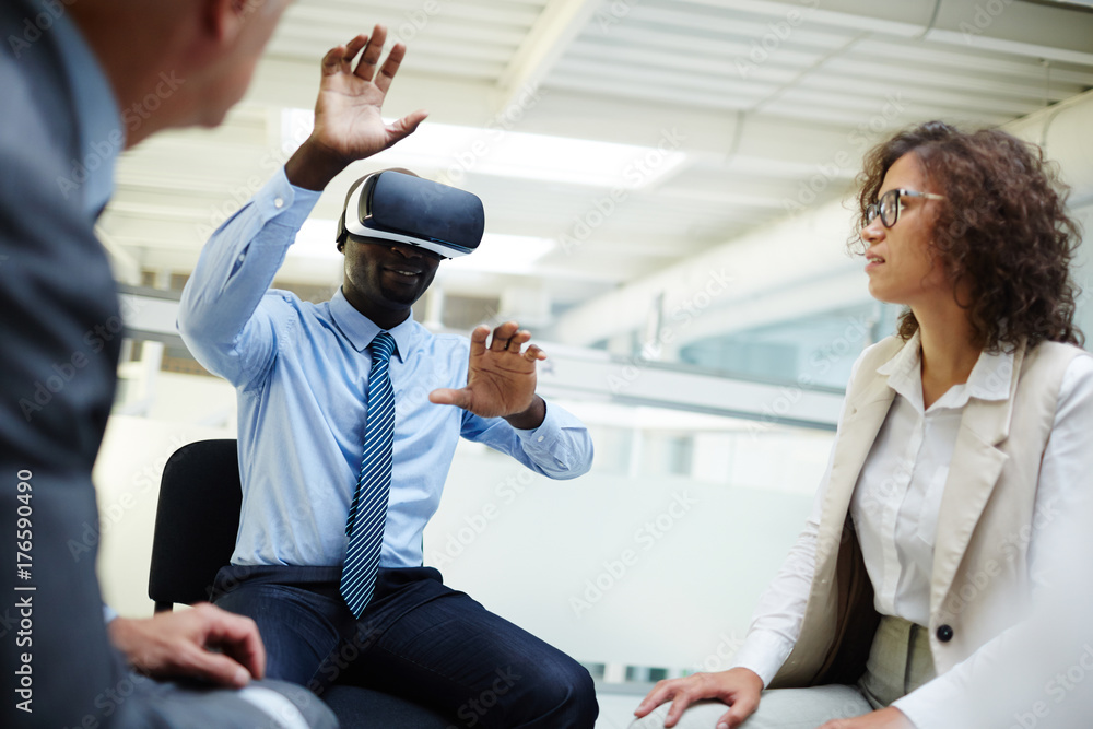 Colleagues looking at businessman with vr headset taking part in virtual conference or webinar Colleagues looking at businessman with vr headset taking part in virtual conference or webinar