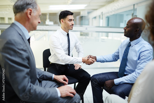 Two intercultural businessmen handshaking after seminar