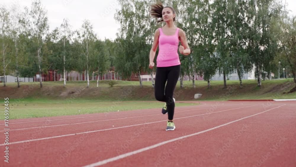 Beautiful Brunette in a pink T-shirt running down the treadmill at the stadium. Beautiful Brunette in a pink T-shirt running down the treadmill at the stadium.