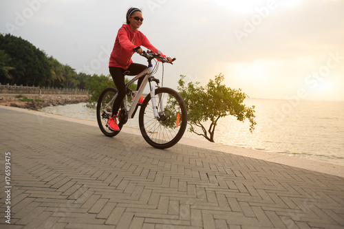 young woman cyclist cycling at sunrise seaside