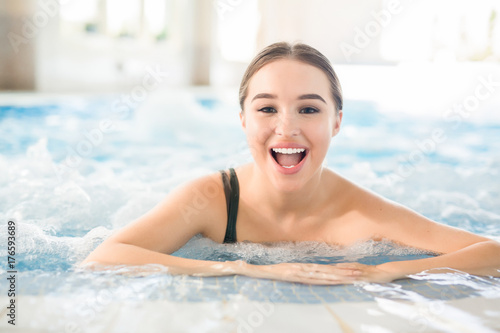 Ecstatic girl enjoying warm and delicate waves of spa whirlpool at resort