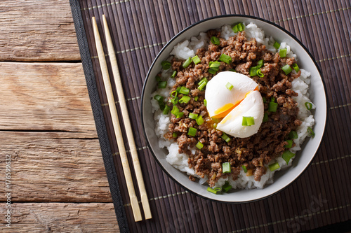 Japanese spicy beef Soboro with egg benedict, rice and green onion close-up. horizontal top view