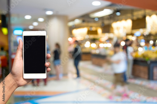 blurred photo and smartphone on shopping mall and people with bokeh.