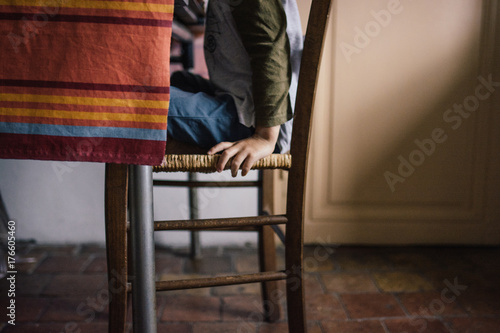 Main de petit garçon assis sur une chaise à table photo