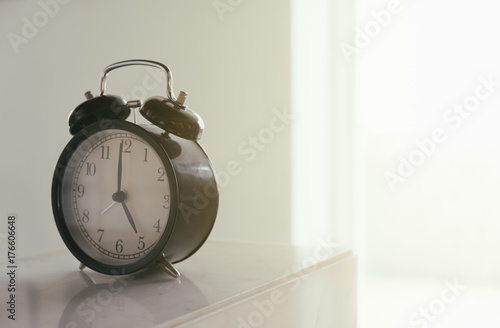 Retro alarm clock with five am in morning or five pm in evening. Vintage style filter photo.