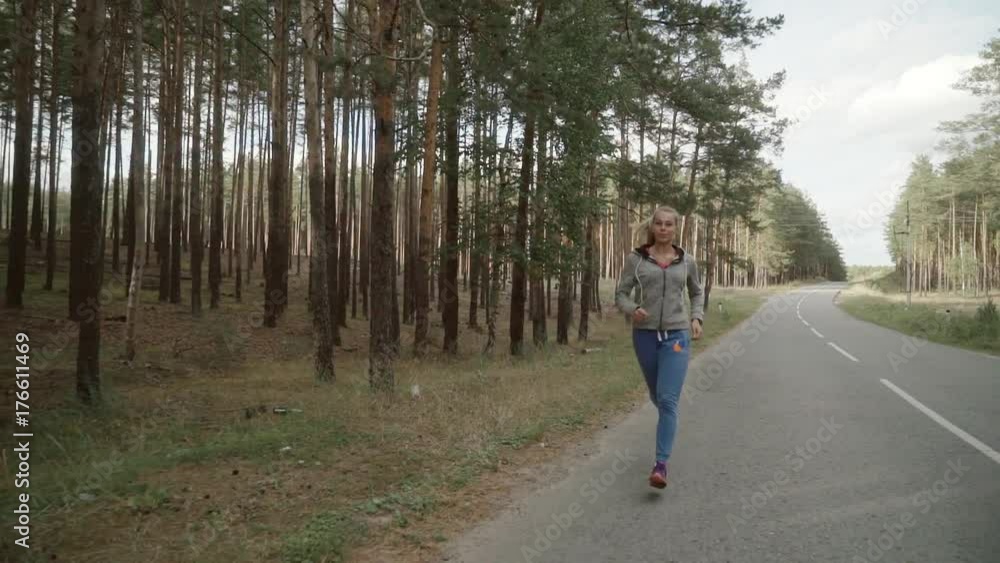The girl runs in a pine forest on the road. The girl runs in a pine forest on the road.