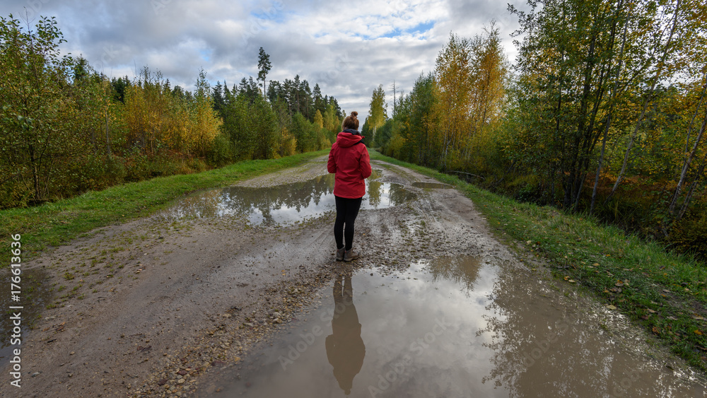 young woman in red jacket enjoying nature on dirt road. Latvia young woman in red jacket enjoying nature on dirt road. Latvia