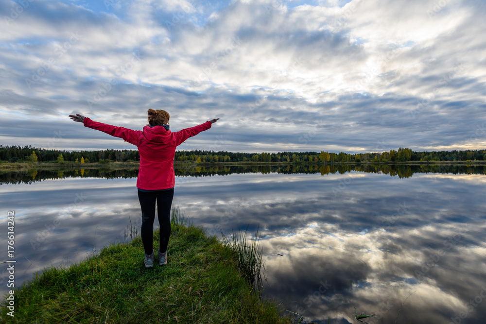 young woman in red jacket enjoying nature on dirt road. Latvia