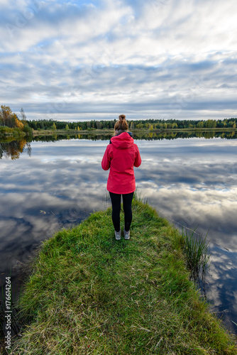 young woman in red jacket enjoying nature on dirt road. Latvia