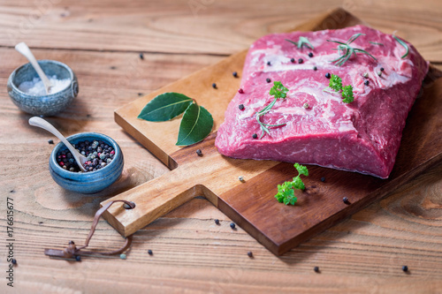 Tender beef sirloin on wooden board with pepper, bay leaf and other spices on rustic wooden table. Selective focus