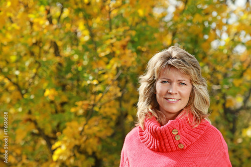 Attractive mature woman in front of yellow autumn leaves photo