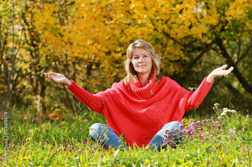 Happy mature woman sitting in autumn surrondings photo