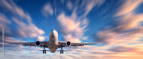 Airplane and beautiful sky with motion blur effect. Landscape with passenger airplane is flying in blurred blue sky with colorful clouds at sunset. Passenger airliner. Commercial aircraft. Private jet