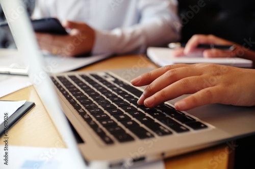 Man working by using a laptop computer on wooden table. Hands typing on a keyboard