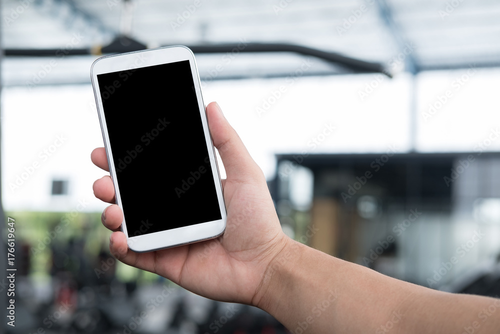 male's hand hold mobile phone in gym. man with smartphone in fitness center. cellphone in health club.