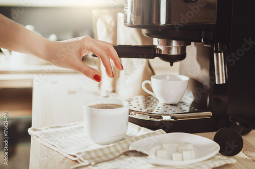 Woman making fresh espresso in coffee maker. coffee machine makes coffee.