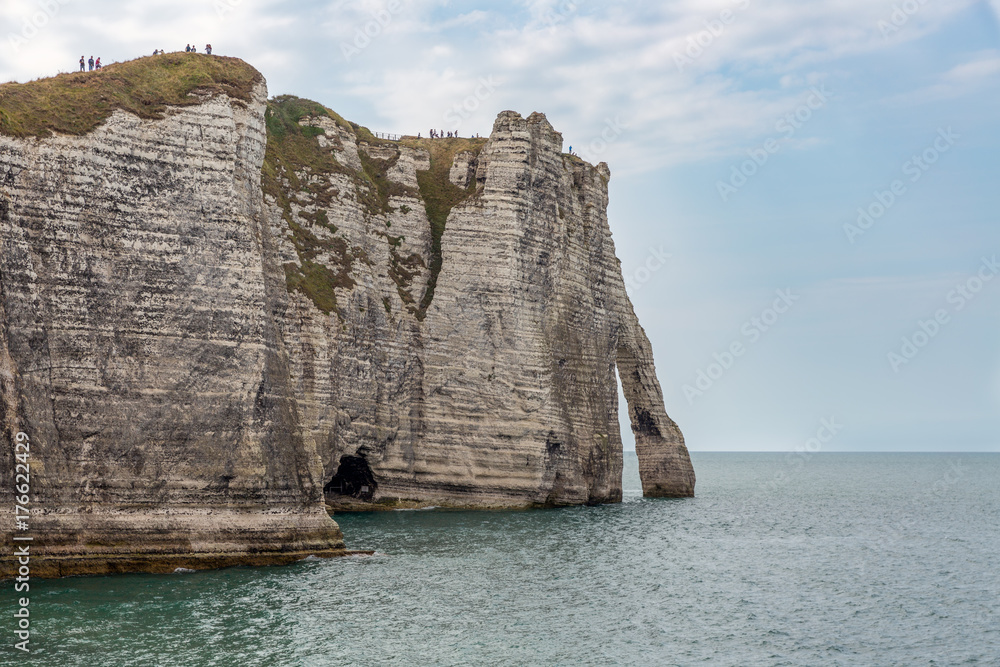 View at people climbing the vertical white limestone cliffs of Etretat in Normandie, France