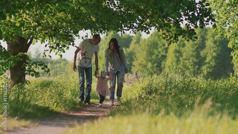 A happy family. Father, mother and a small charming daughter run along the path in a forest park, holding hands. Summer. The sun. Love. A happy family. Father, mother and a small charming daughter run along the path in a forest park, holding hands. Summer. The sun. Love.
