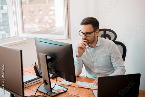 Fototapeta Man working on computer in modern office interior.